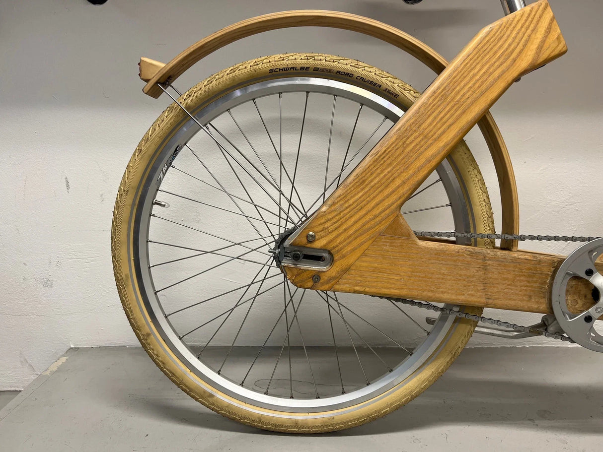 Bakre hjul och ram i trä på cykel med beige däck och kedja
