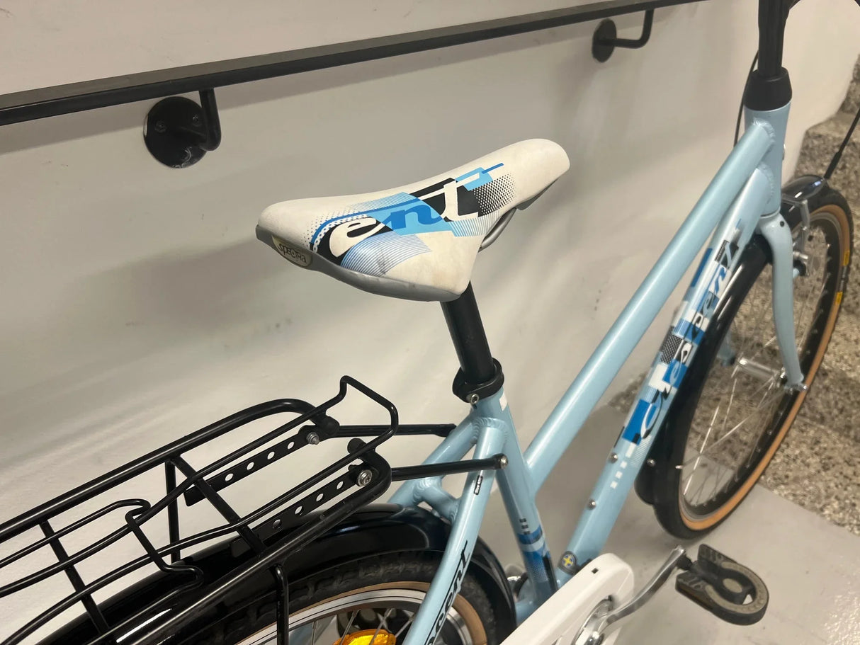 Ljusblå Crescent cykel med vit sadel, svart pakethållare och beige däckkant