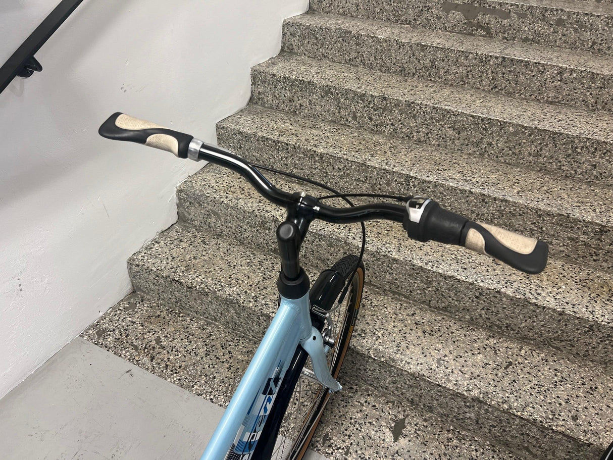 Blå trek citycykel med böjt styre och svarta handtag på trappa