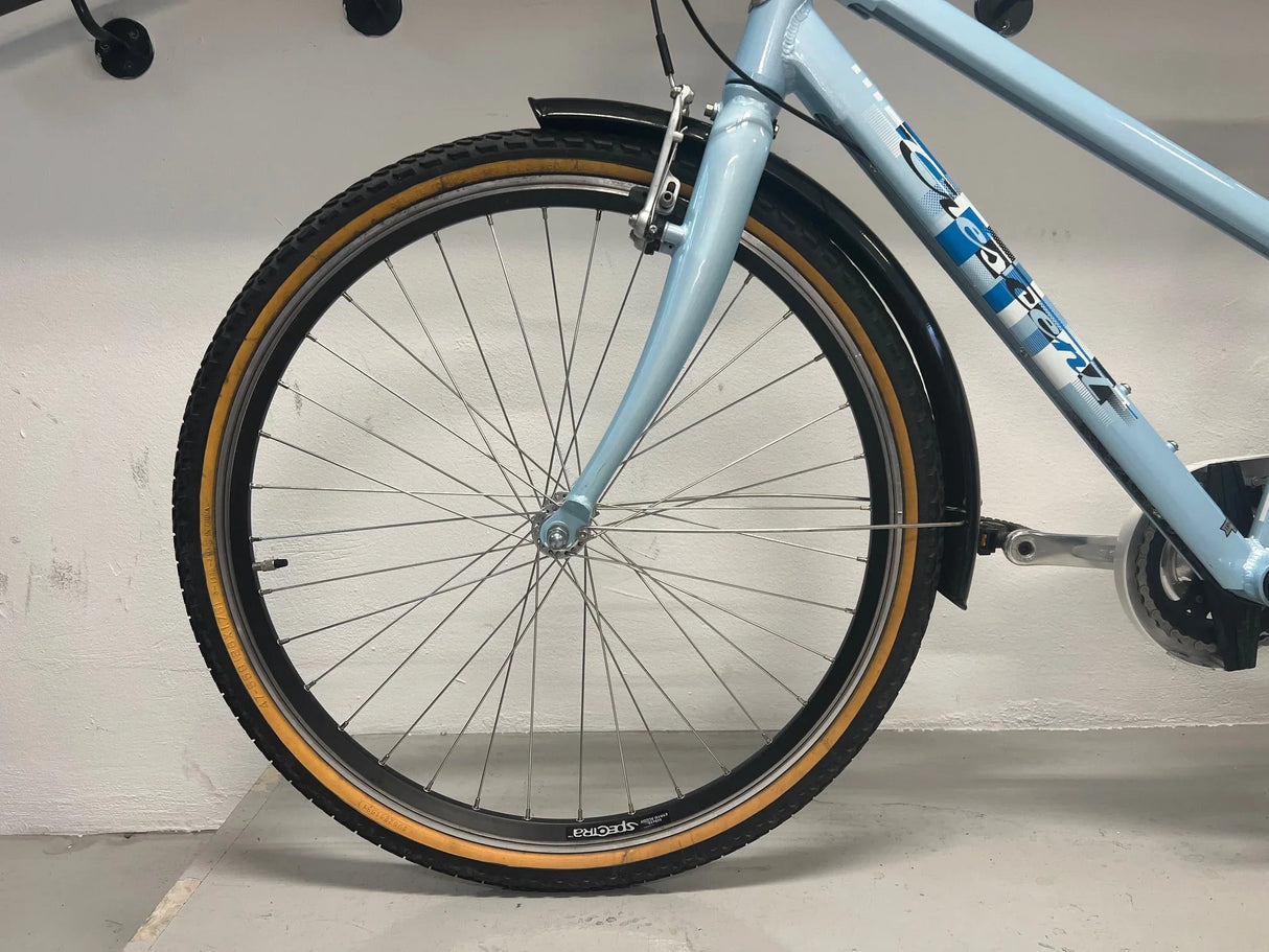 Framhjul på ljusblå Crescent cykel med svart stänkskärm och bruna däcksidor