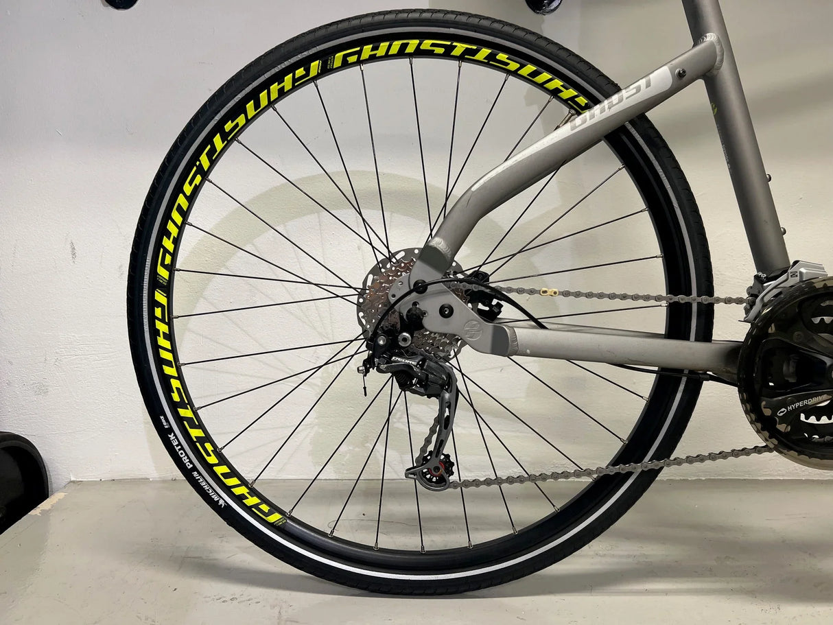 Bakhjul på silverfärgad cykel med gula Ghost-hjul och Shimano Deore växelsystem