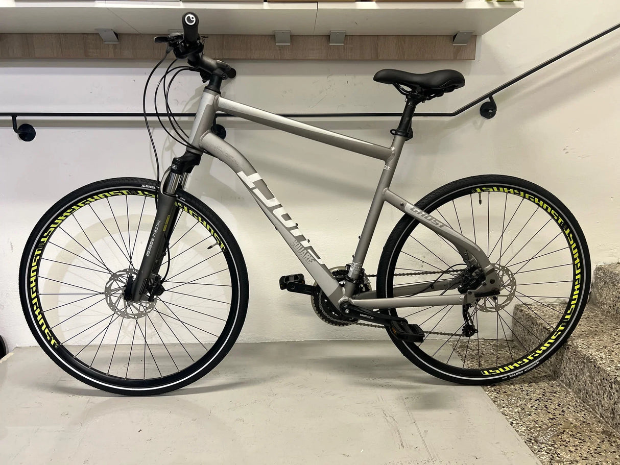 Grå Ghost square mountainbike med skivbromsar och Shimano-växlar, svart sadel och gula däckmärken