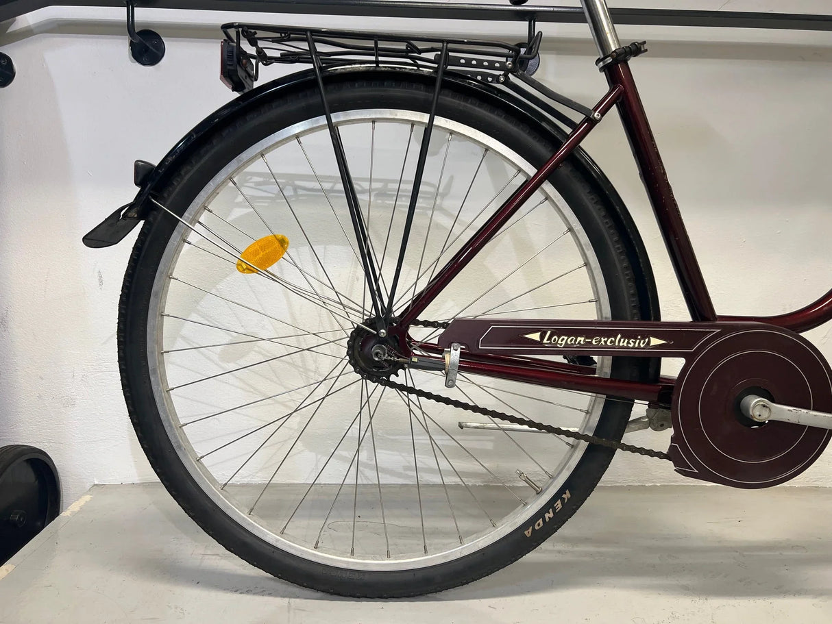 Bakre hjul på vinröd Logan-exclusiv cykel med svart Kenda däck och svart pakethållare