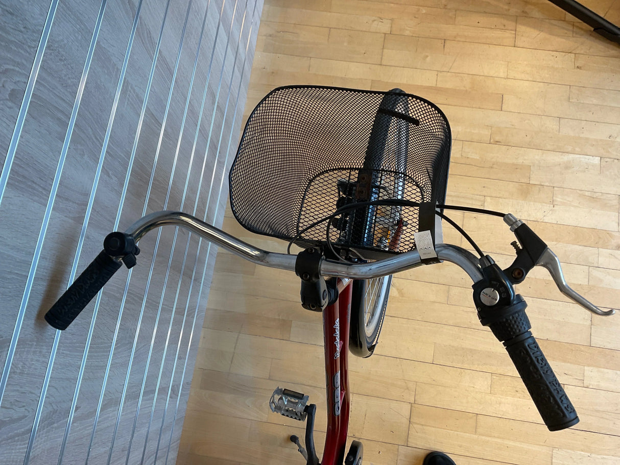 Rött cykelstyre med svart korg fram och handbroms på träparkettgolv