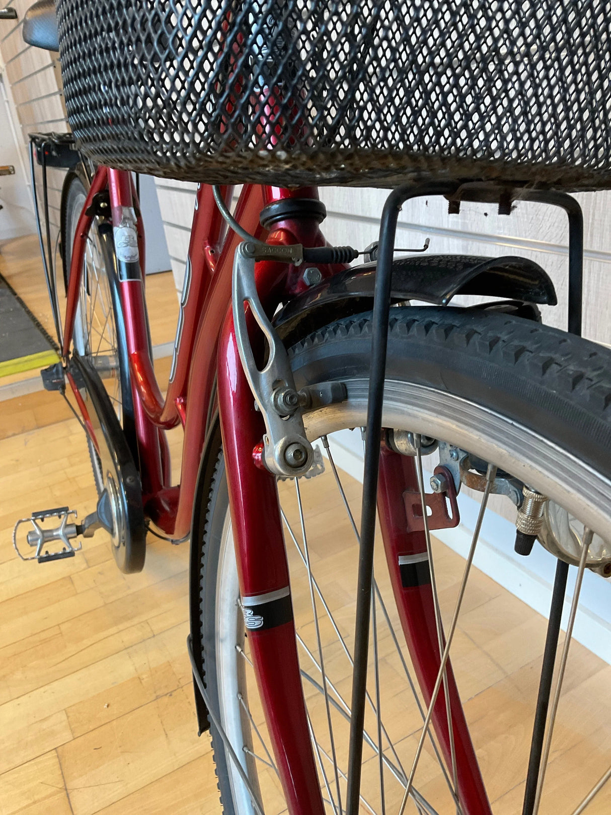 Röd cykel med svart metallkorg fram och däck med grovt mönster nära