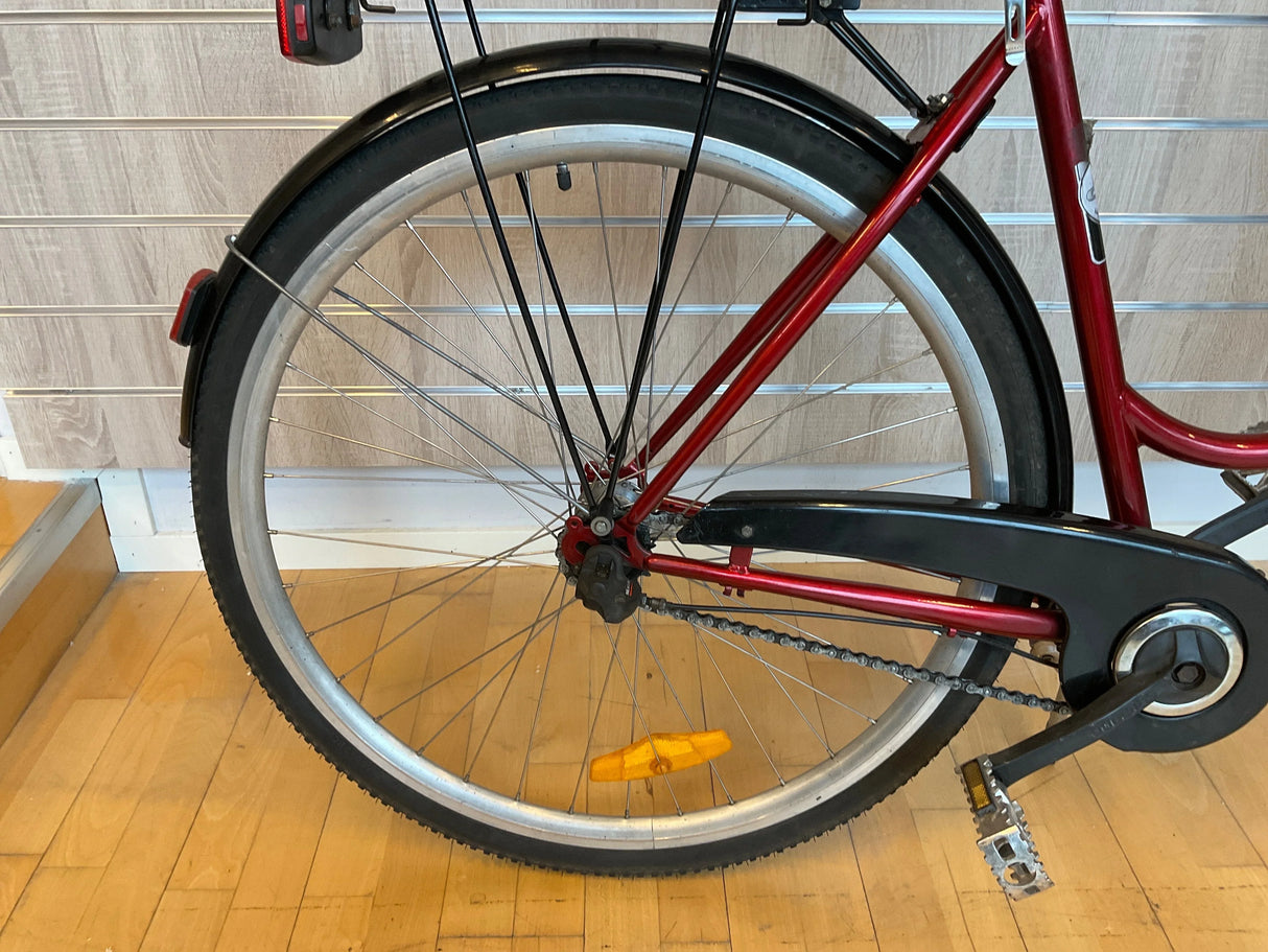 Bakre hjul på röd cykel med svart kedjeskydd och orange reflex