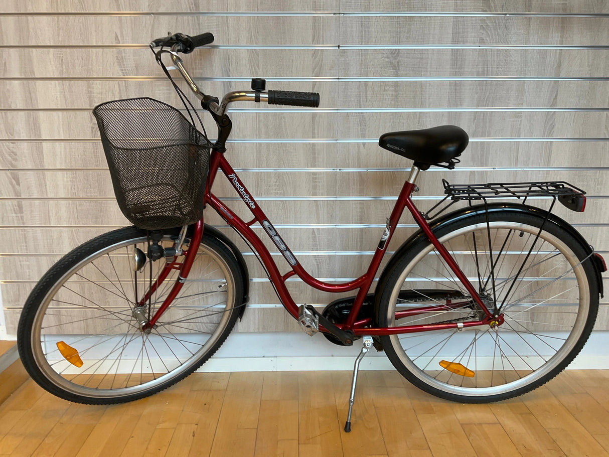 Röd damcykel med svart korg fram, pakethållare och reflexer på hjulen
