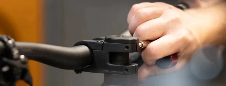 Hand som skruvar en cykelstyreklämma med insexnyckel