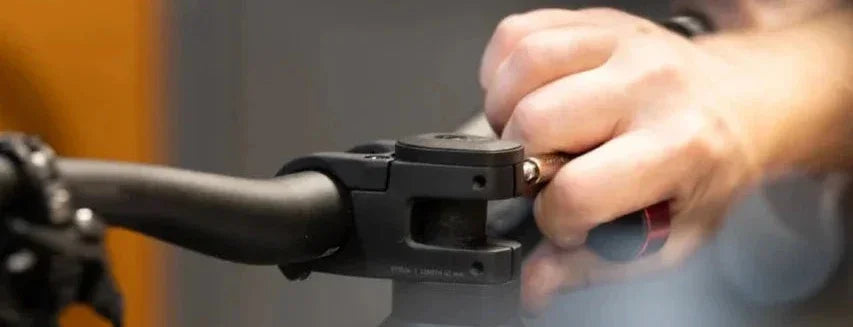 Hand som skruvar en cykelstyreklämma med insexnyckel