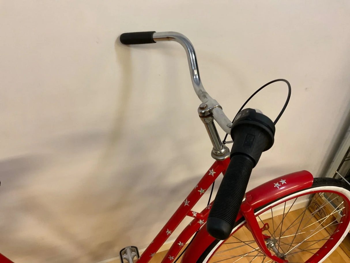Röd cykel med svart handtag, silverstjärnor och vit kant på däcken