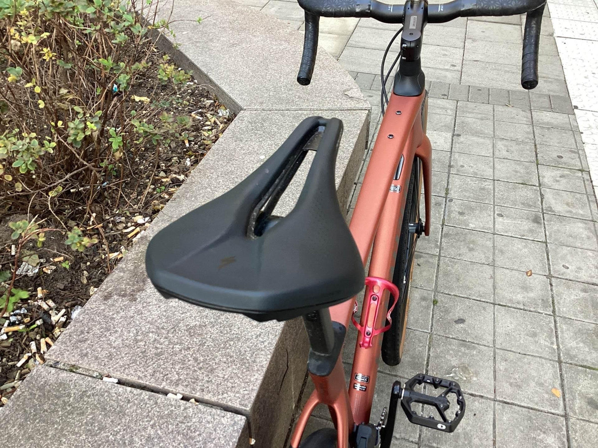 Orange racercykel med svart sadel och rosa flaskhållare i närbild