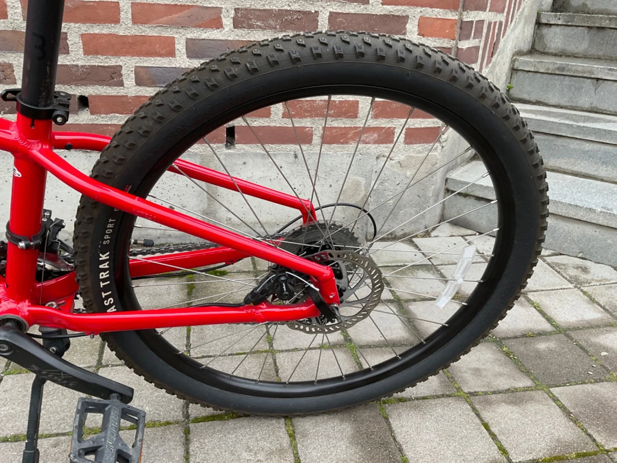 Rött mountainbikes bakhjul med tjocka, mönstrade däck och skivbroms