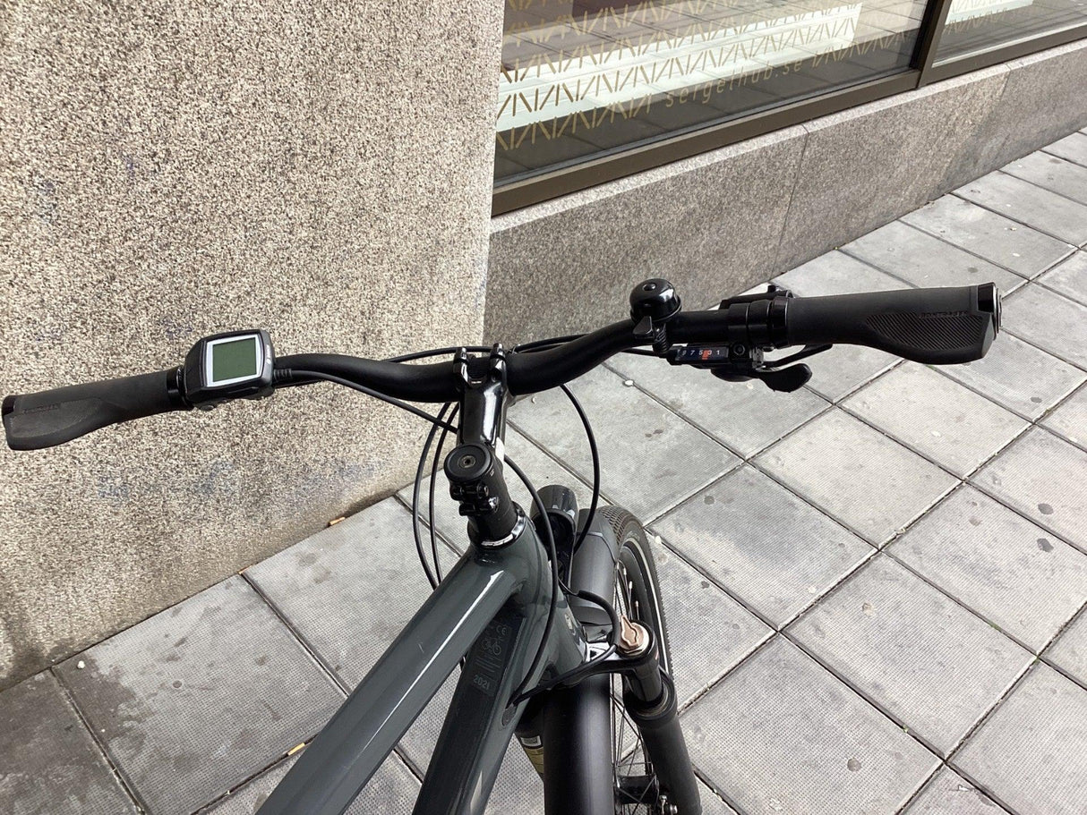 Svart styre på modern elcykel med digital display och växelreglage på grå trottoar