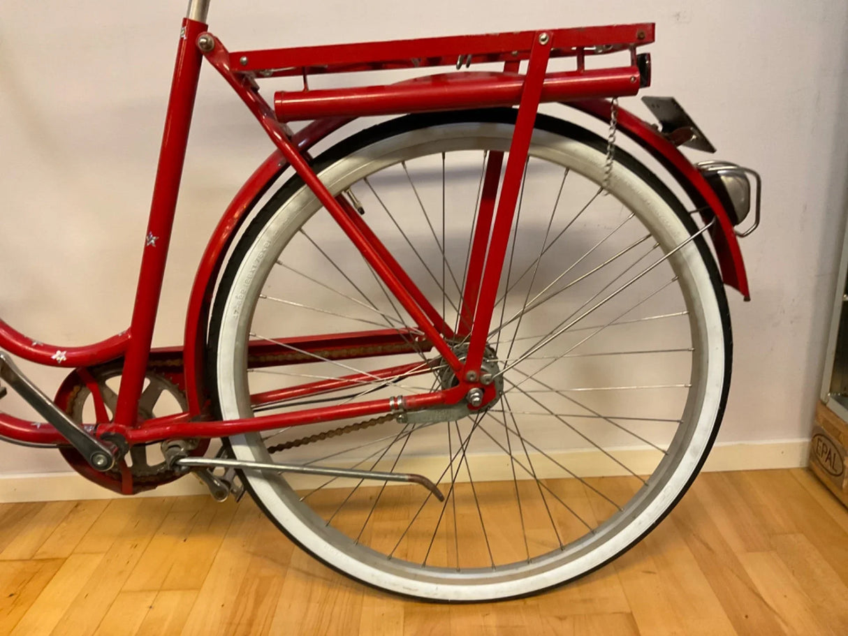 Röd cykels bakhjul med vit däckremsa och pakethållare i metall