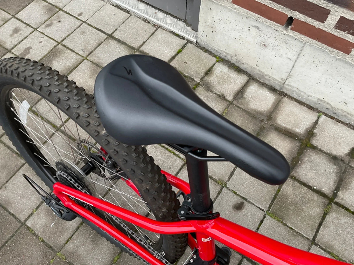 Svart cykelsadel på röd mountainbike med grovmönstrade däck