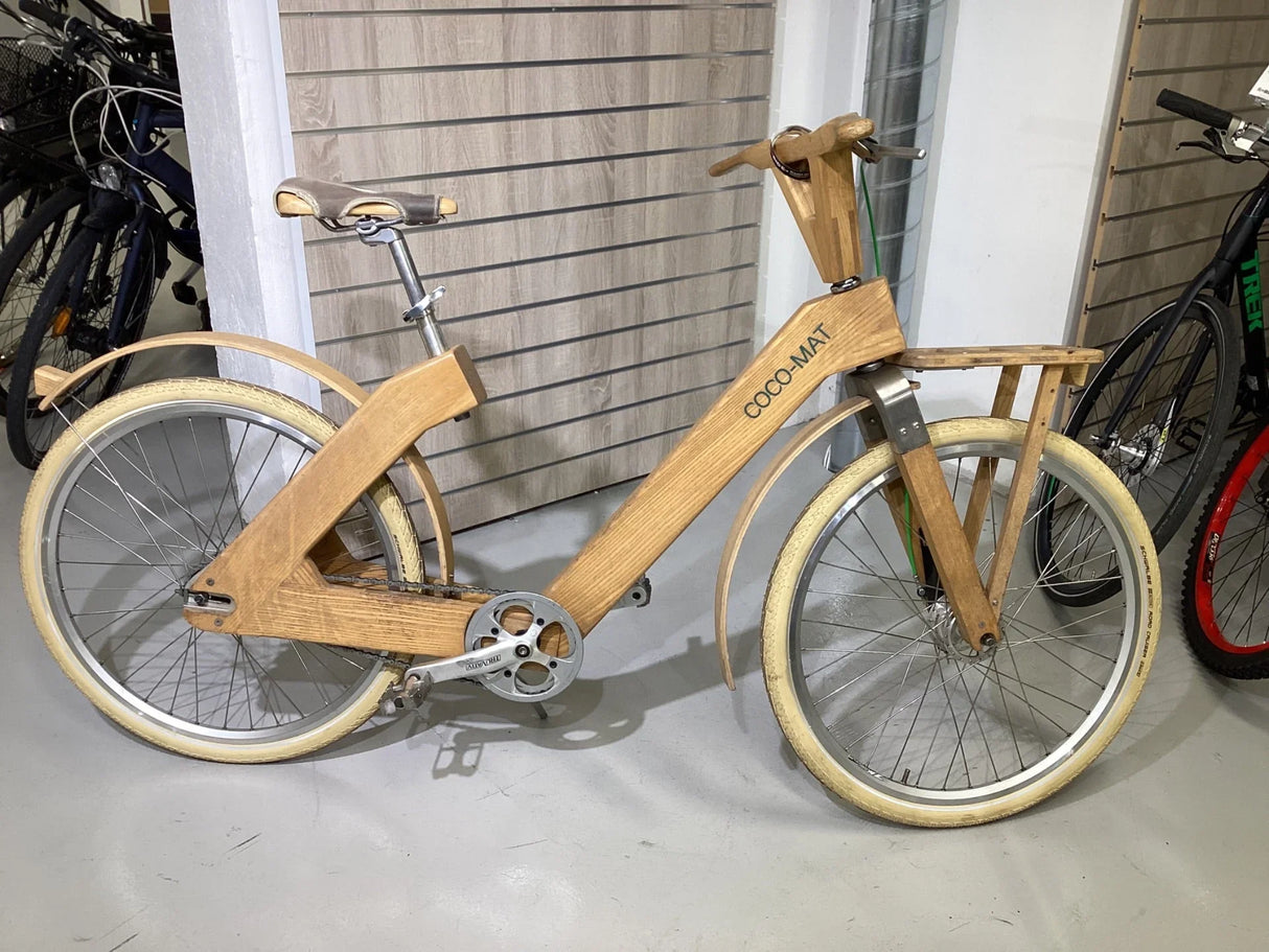 Coco-Mat träcykel med unikt designad ram och vita däck i cykelutställning