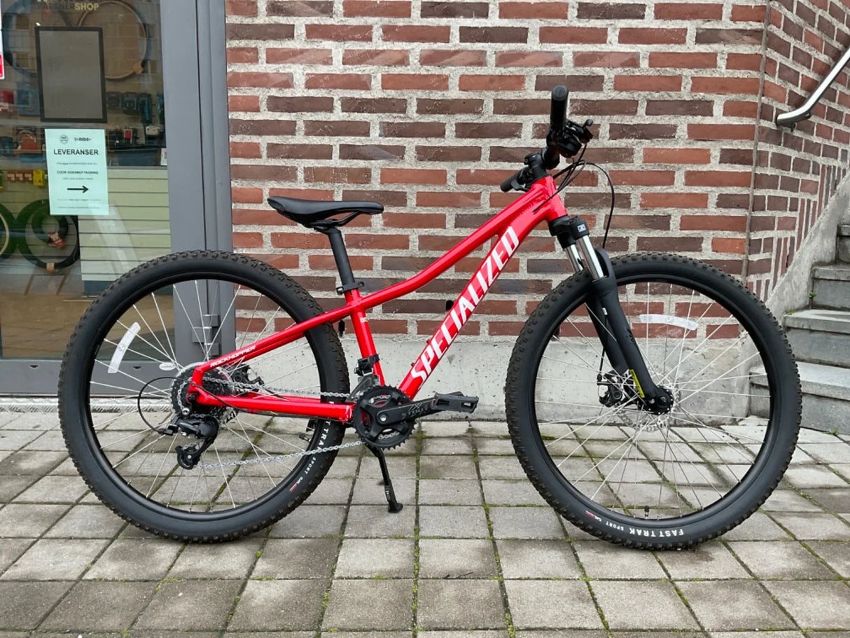 Röd Specialized mountainbike med tjocka däck och skivbromsar på stenplattor