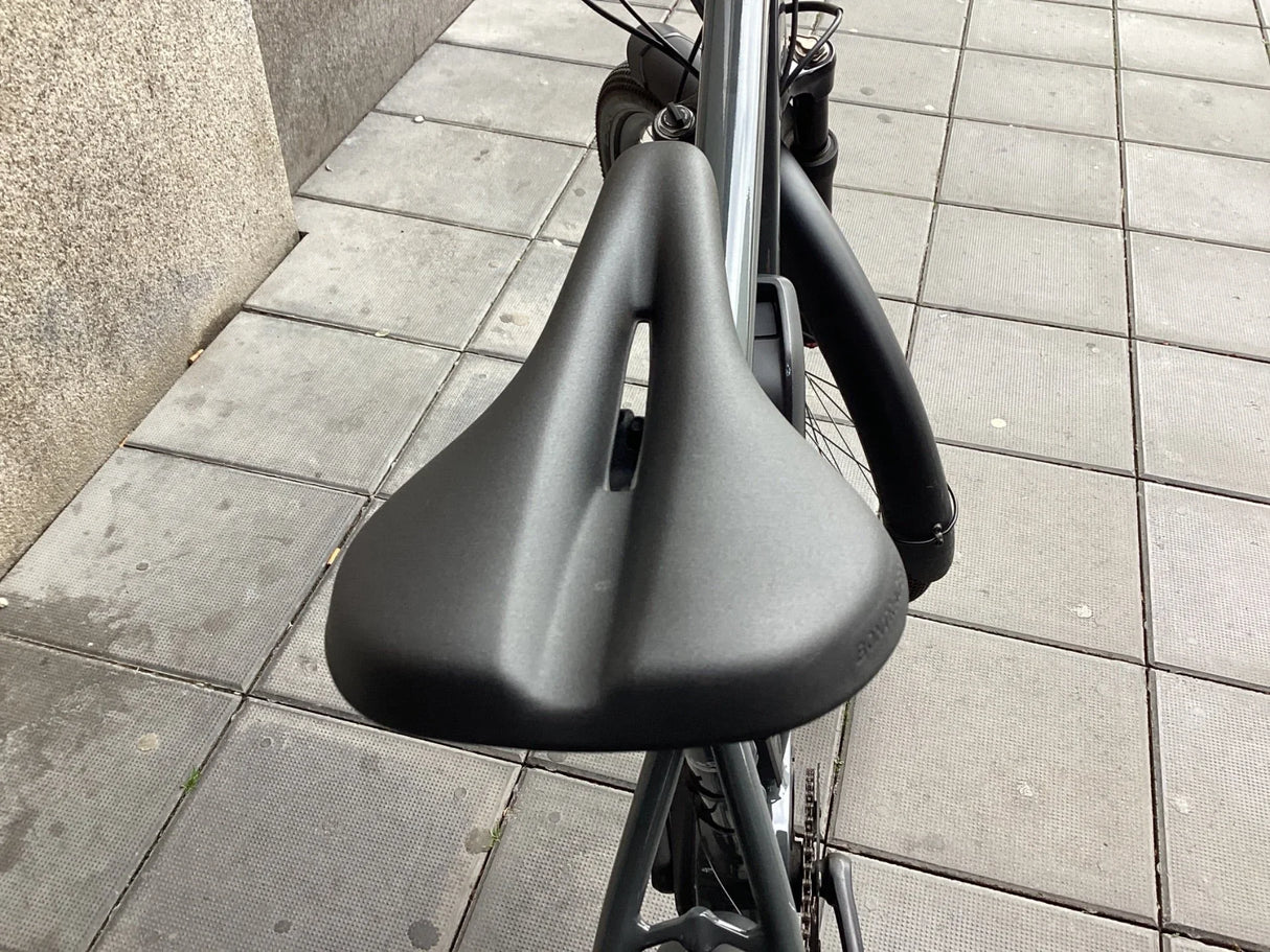 Svart cykelsadel med ergonomisk design och ventilationsöppning på grå trottoar