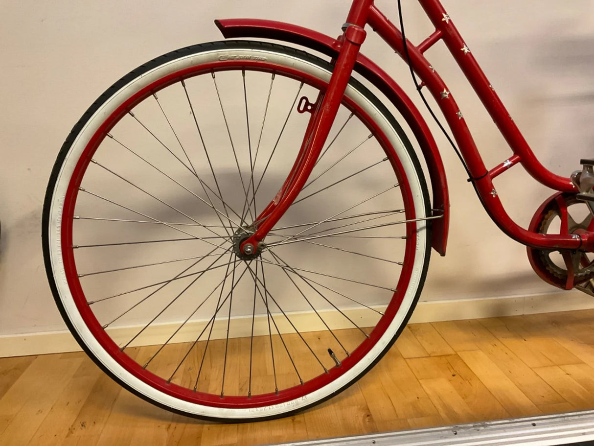 Rött cykelhjul med vita däck och femuddiga stjärnor på ram