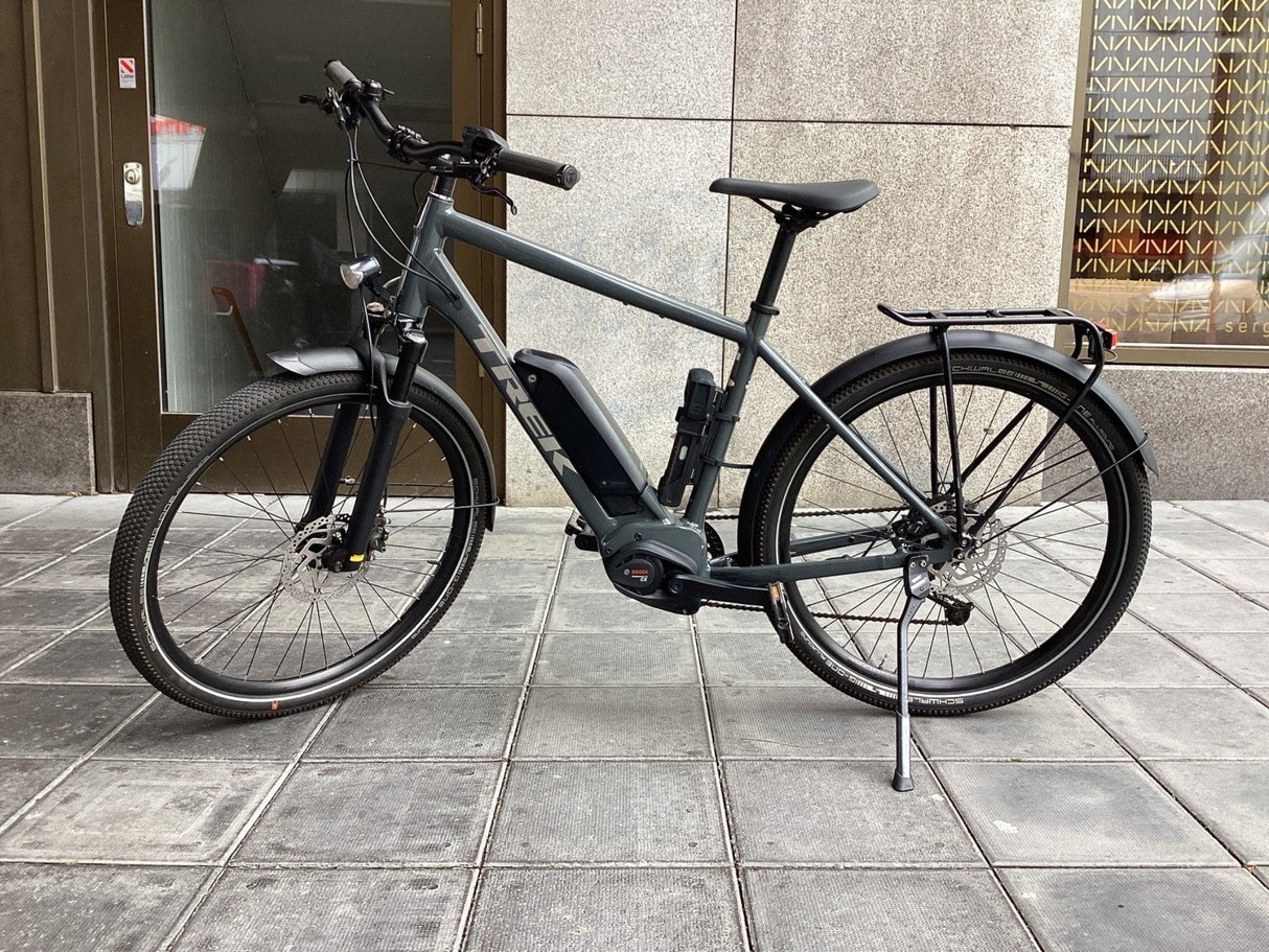 Grå TREK elcykel med Bosch motor, skivbromsar och pakethållare på trottoar