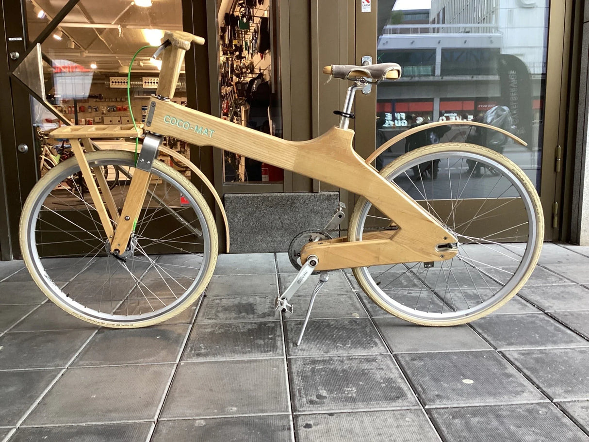 Miljövänlig trädcykel med träram och beige däck märkt COCO-MAT