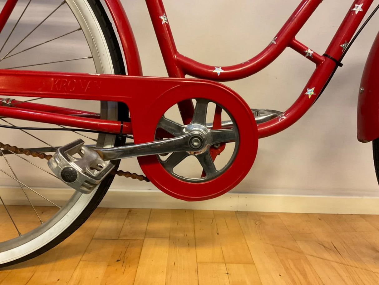 Röd cykel med skydd över kedja och pedal i aluminium
