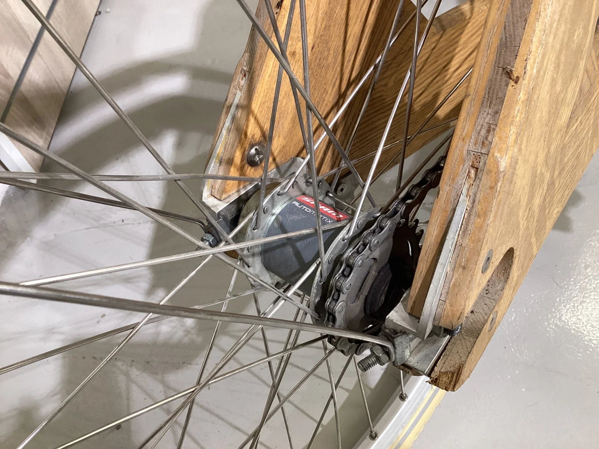 Närbild på cykelhjul med Shimano nav och kedja monterad i träfäste