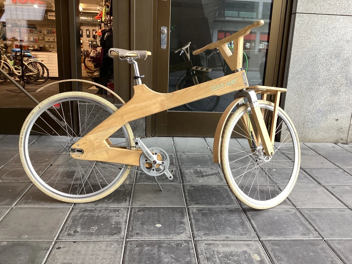Unik träcykel med ljusa däck, lädersadel och COCO-MAT branding på sidan