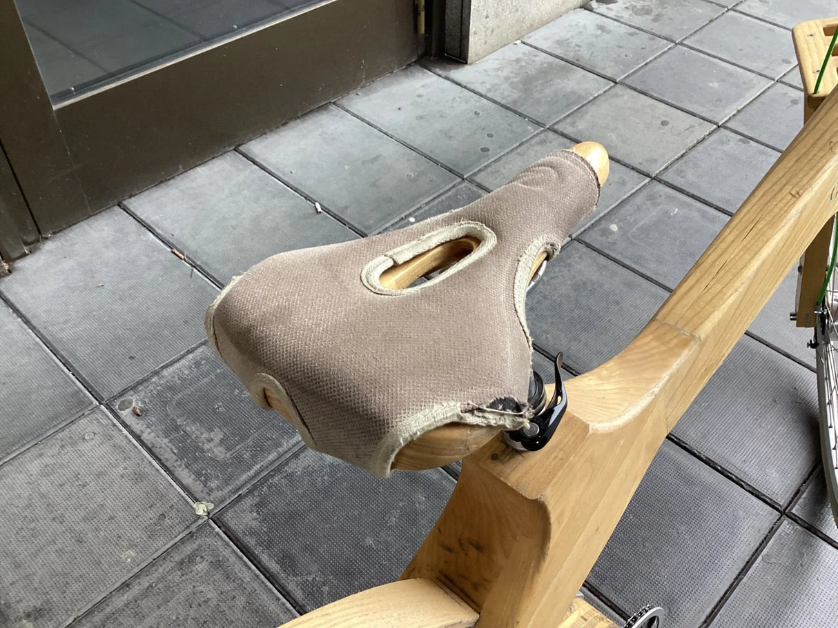 Cykelsadel i trä med slitstarkt brunt tyg och handtag på modern träcykel