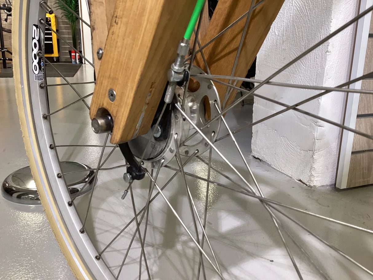 Närbild på cykelhjul med träram och metall ekrar, beige däck med vit kant, cykelhjulsdetaljer