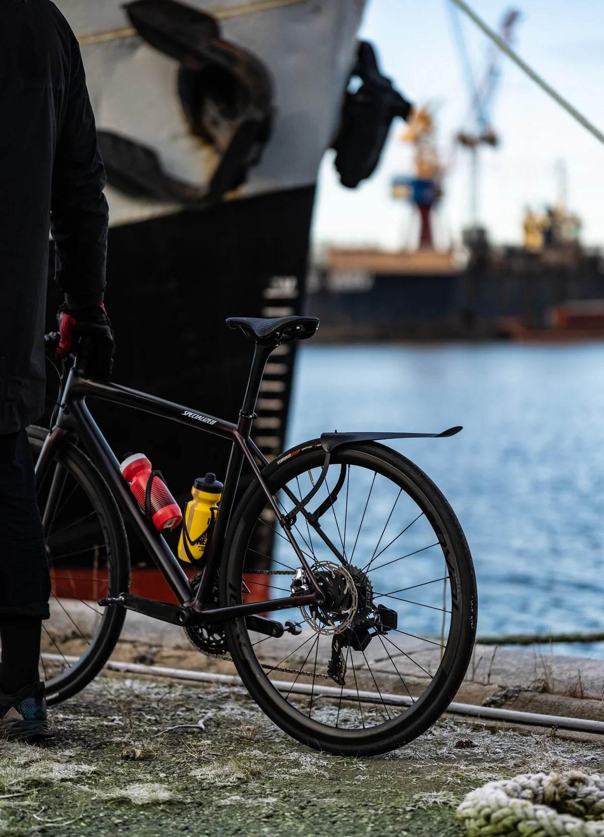 Landsvägscykel Specialized med vattenflaskor vid kaj intill stort fartyg