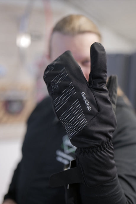 Svart GripGrab-vante med reflexprickar, hålls upp av person