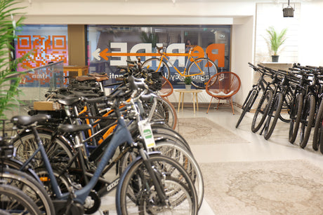 Cykelbutik med elcyklar, stadscyklar och en orange racercykel på display