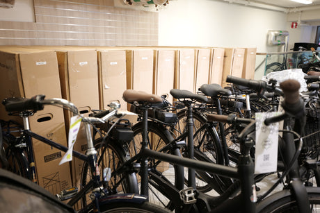 Svarta elcyklar på rad framför stora cykelkartonger i butik