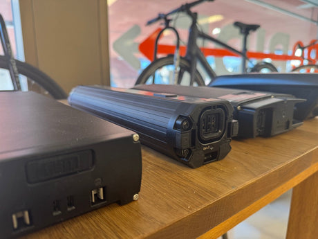 elcykelbatterier och laddare på träbord, elcykel synlig