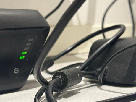 Närbild på uppladdningsbar powerbank med gröna LED-lampor och svarta elkablar