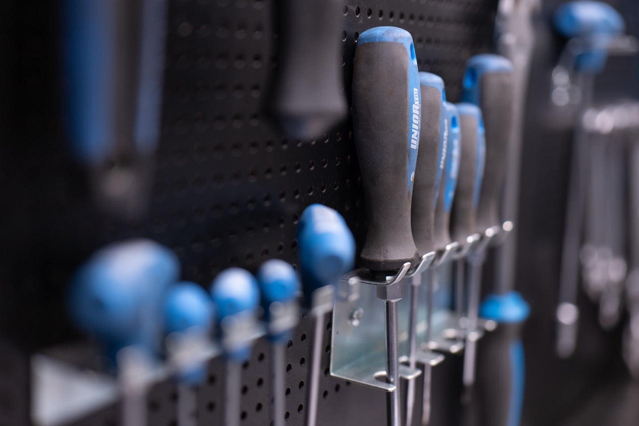 Skruvmejslar med blå handtag organiserade på verktygstavla