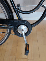 cykelpedal och vevarm i metall, kedja och svart kedjeskydd