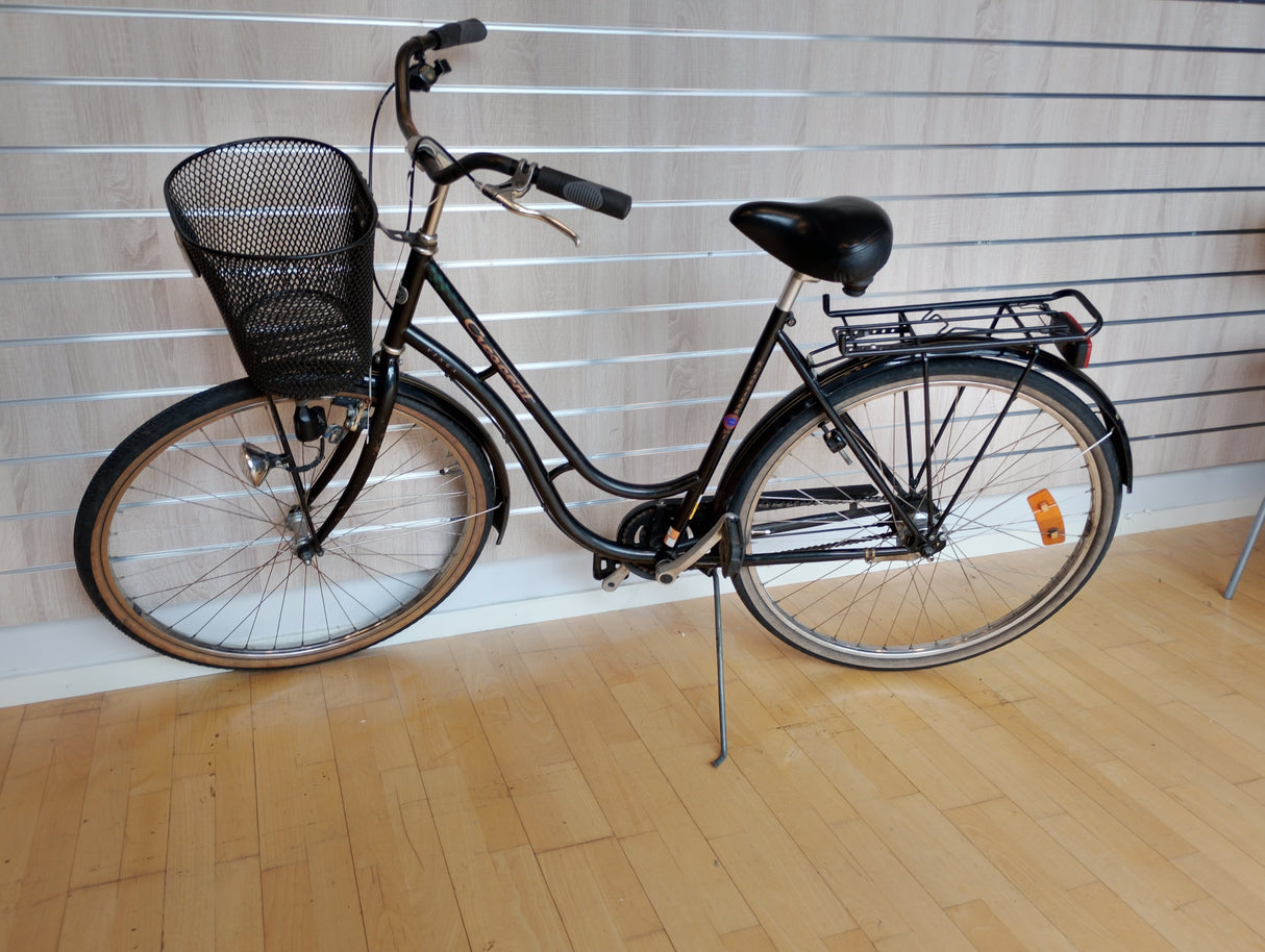 Svart damcykel med cykelkorg, pakethållare och upprätt sittställning