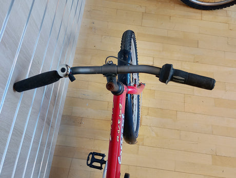 Rött cykelstyre med svarta handtag och SRAM-växel, mountainbike framhjul syns