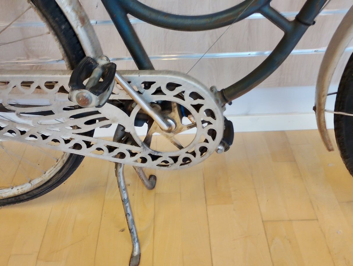 gammal cykel med dekorerat kedjeskydd, pedal och stödstativ synliga