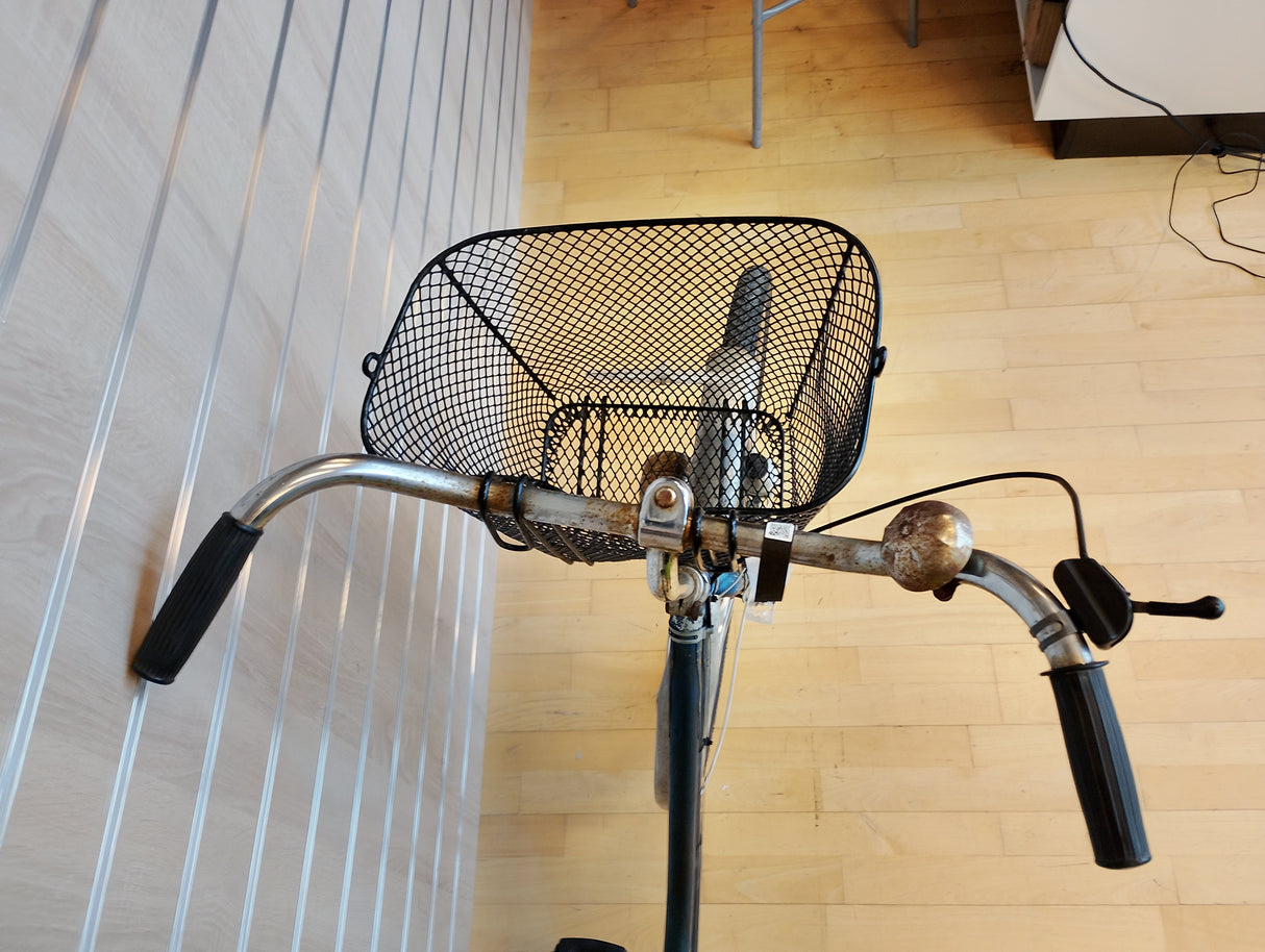 Cykelstyre med svart metallkorg och ringklocka, närbild framifrån