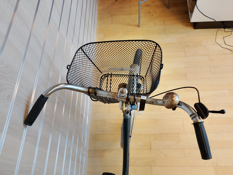 Cykelstyre med svart metallkorg och ringklocka, närbild framifrån