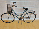 Blå damcykel med korg fram och pakethållare bak, klassisk retrocykel.