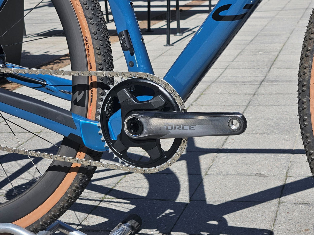Cykelns drivlina med Sram Force vevarm, blå ram och bruna däck för gravelbike