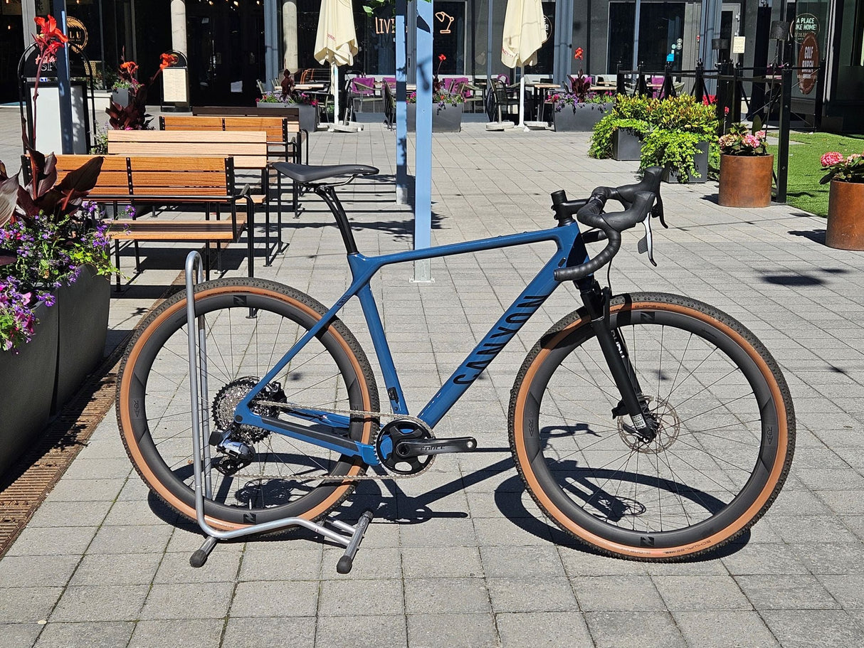 Blå Canyon gravelcykel med breda däck på cykelställ, snygg ram och skivbromsar