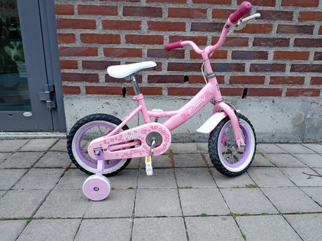 rosafärgad barncykel med stödhjul och vit sadel, märke Pollux