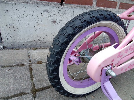 Närbild på bakhjul med rosa och lila cykelram och knoppdäck