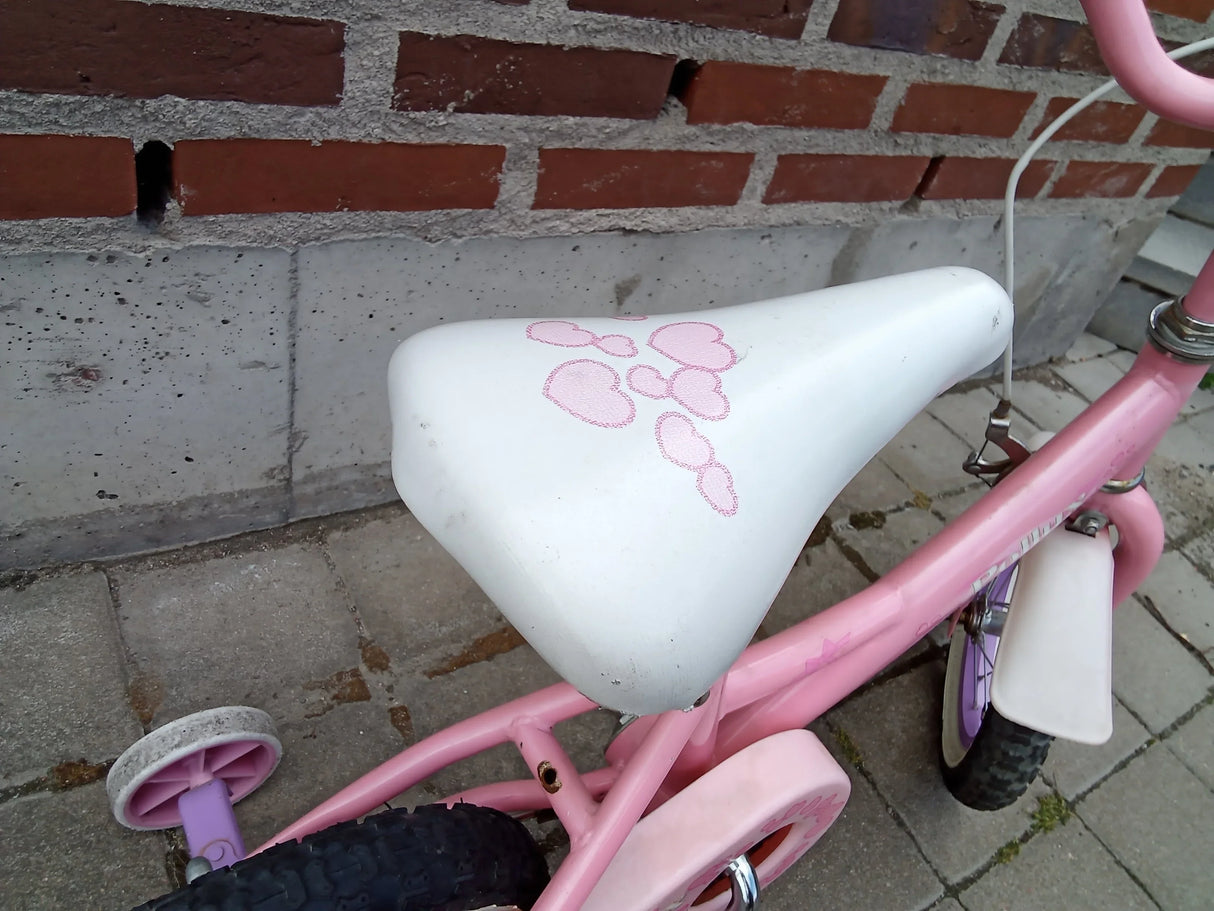 Barncykel i rosa med vitt säte dekorerat med rosa hjärtan och stödhjul