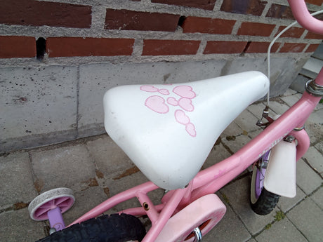 Barncykel i rosa med vitt säte dekorerat med rosa hjärtan och stödhjul